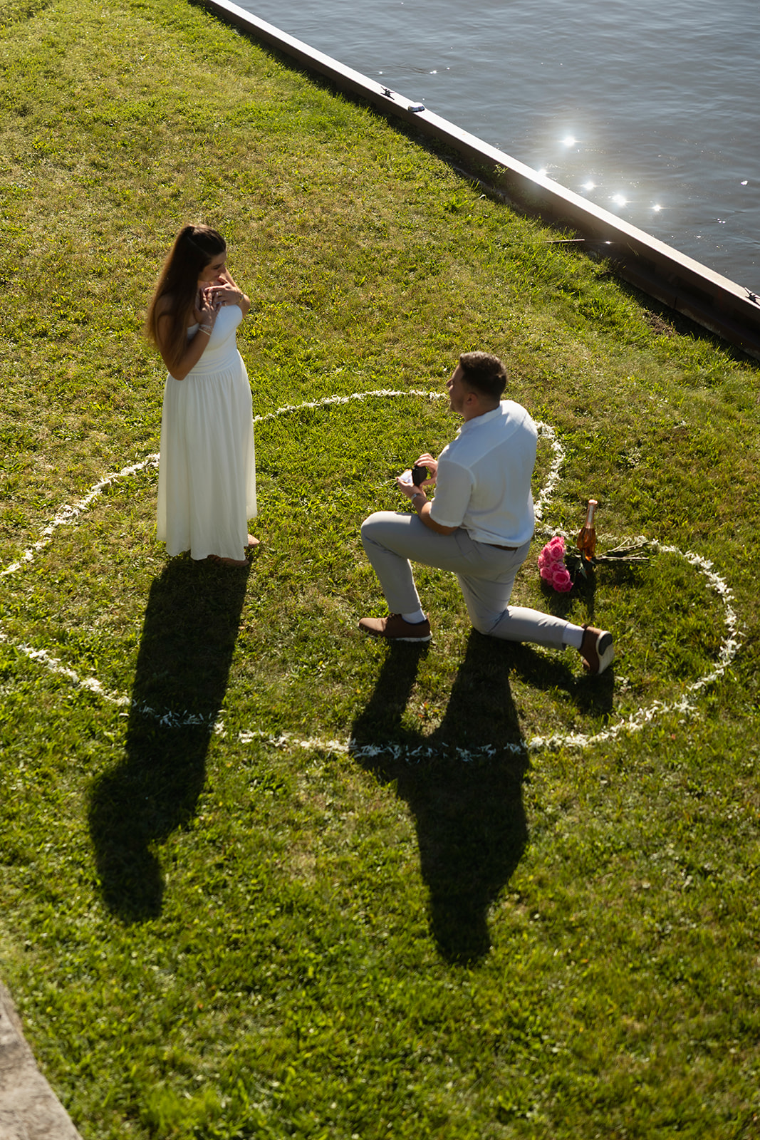 Andrew proposing to Laura inside a floral heart beside the water
